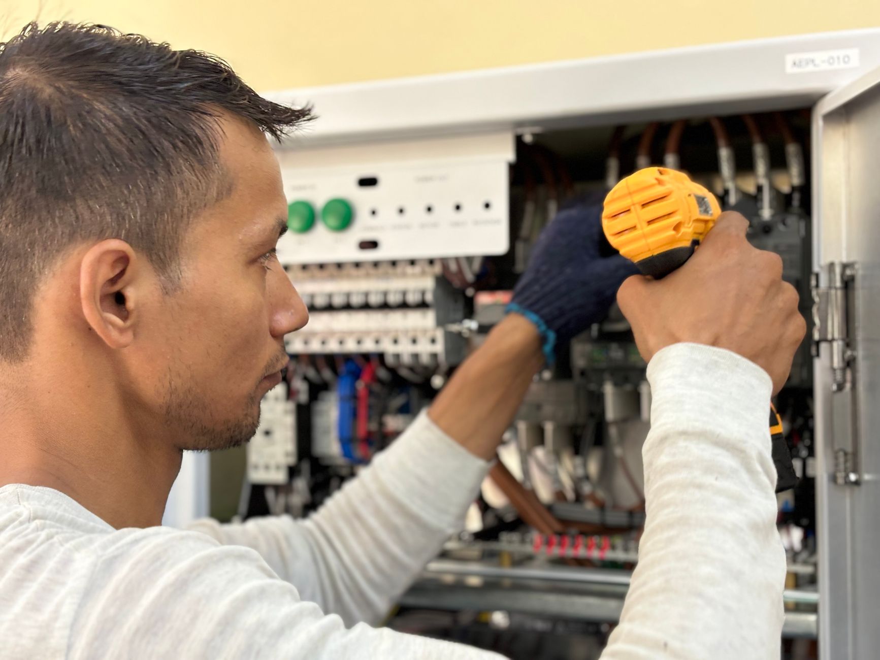 Technikus fúróval dolgozik egy elektromos kapcsolótáblán