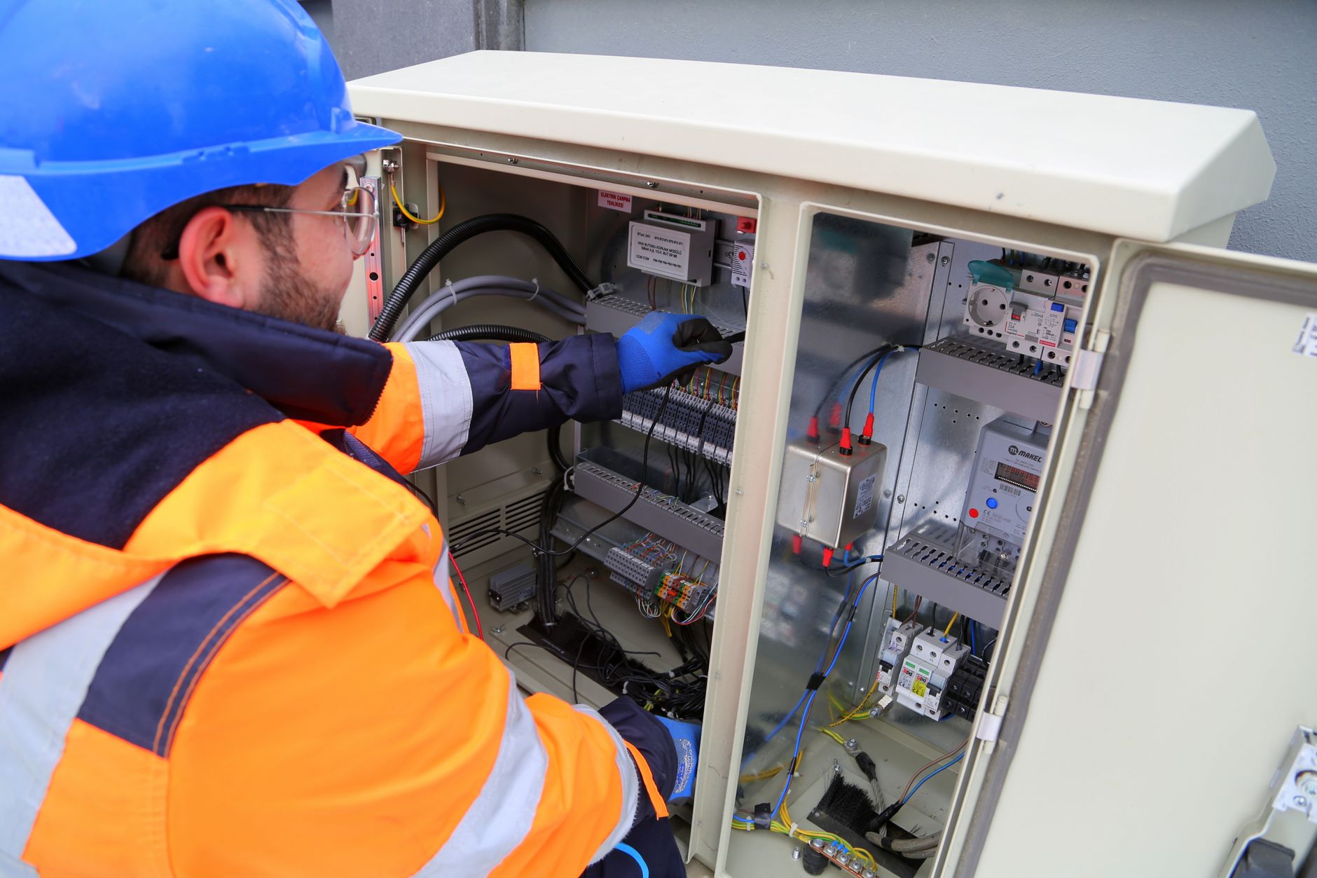 Mérnök védőfelszerelésben kültéri elektromos kapcsolószekrényt szerel